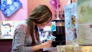 一个<strong>女孩</strong>坐在咖啡馆的桌子边画画