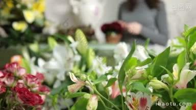 <strong>背景</strong>中的花店里陈列着大量的鲜花，女子在安排情人节玫瑰心花束
