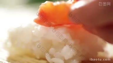 把一块三文鱼放在<strong>米饭</strong>寿司卷上
