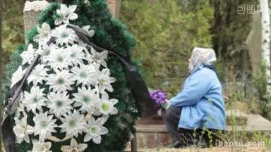 一位老妇人在墓地的坟墓前