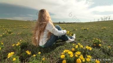 金发碧眼的小女孩坐在春天的野黄牡丹草地上