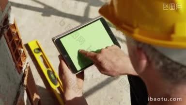 建筑工人和新建筑成年男子在工作时戴安全帽，并使用数字平板电脑输入数据
