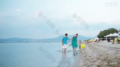 年轻的家庭在海边享受一个夏天，沿着海滩在浅水和小男孩散步