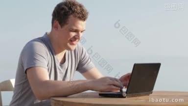 一名男子在小型笔记本电脑上打字，他坐在享受夏日的阳光，而假期允许他