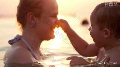 日落时分，在海水中沐浴的母亲在亲吻她年幼的孩子