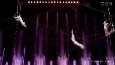 空中杂技表演在马戏团紫色喷泉的背景