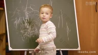 一个有创意的小男孩在<strong>幼儿园</strong>的<strong>教室</strong>里在黑板上画画，他回过头来寻求认可