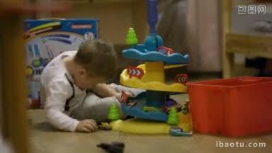 小男孩坐在游戏室的地板上玩塑料车库和微型汽车