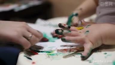 用彩色指画画的母亲和儿子的手的特写