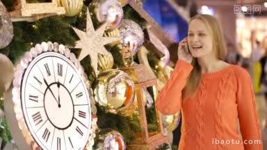 一个女人在一棵巨大的圣诞树旁打电话，圣诞树上有很多装饰物和<strong>时钟</strong>