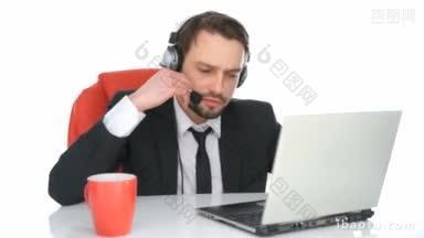 英俊的呼叫中心接线员坐在笔记本电脑前，用耳机和<strong>客户</strong>通话