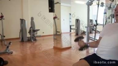 一个成熟的男人在健身房用哑铃锻炼的镜头