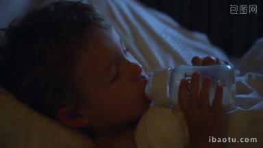 一个小男孩在睡觉前从<strong>瓶子</strong>里喝<strong>牛奶</strong>的特写镜头