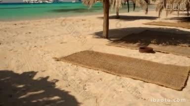 多莉拍摄的空海滩与太阳伞和垫子清澈的蓝色大海与游艇在背景