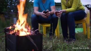晚上，男人和女人在户外的火炉边喝茶取暖