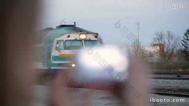 一个女人用智能手机拍摄即将到来的火车的特写镜头，镜头的<strong>焦点</strong>发生了变化