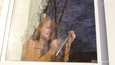 年轻的女人看着窗外，画着窗外的草图，窗外的树木映在玻璃上