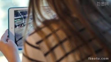 一个女人拿着平板电脑从窗户向城市拍照的多利特写镜头