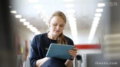 年轻体贴的妇女使用触控板坐在候<strong>诊室</strong>的背景离焦内部