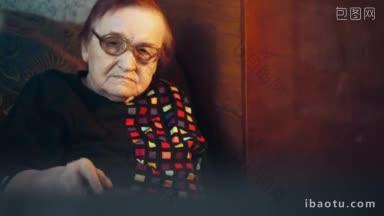 <strong>戴眼镜</strong>的老妇人坐在沙发上看电视，用遥控器换频道