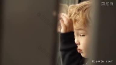 小男孩看着<strong>窗外</strong>，他的脸和手紧紧地贴在窗户上，在玻璃上倒映着