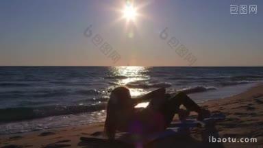 健身运动妇女做腹部<strong>紧缩</strong>在海滩上的锻炼在日落