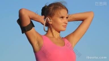 健身女子戴着耳机和<strong>运动</strong>智能<strong>手机</strong>袖标，望向远方的蓝天
