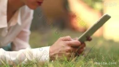 年轻的女孩浏览她的平板<strong>电脑</strong>躺在草地上在公园<strong>职员</strong>聊天在她的闲暇时间