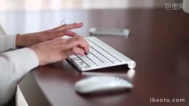 年轻的女商人在办公室的电脑上工作，敲击键盘和鼠标写电子邮件