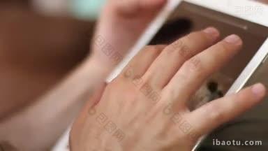 <strong>一个</strong>男人用他的ipad上网，两只手碰着平板电脑屏幕浏览