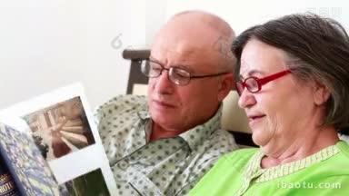近距离拍摄一对相爱的老夫妇在床上看一本充满回忆的相册