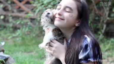 漂亮的小女孩抱着她可爱的棕色和白色的小狗狗在外面的花园