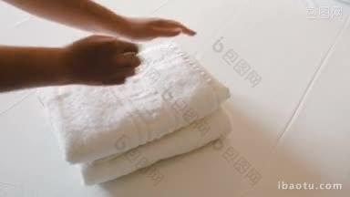 特写的女人把两条干净的<strong>毛巾</strong>放在床上的<strong>白色</strong>床单上
