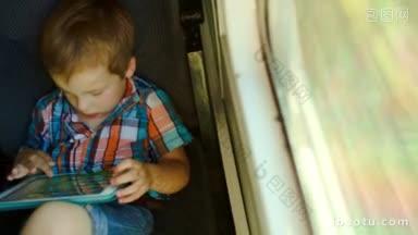 高角度视角的小男孩坐在火车的窗口和使用触摸板