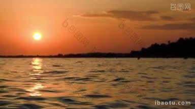 美丽的橙色日落在黑暗的波浪太阳反射在水中