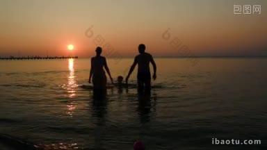夕阳西下，父母和儿子手牵着手从海里走出来的黑色剪影