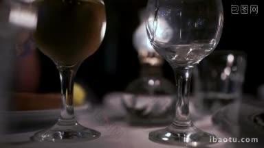 倾斜的特写镜头倒白葡萄酒到一个满杯站在附近
