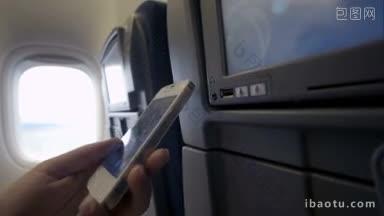 在飞<strong>机上</strong>，一名女子用usb线将智能手机连接到座椅显示器上的特写镜头