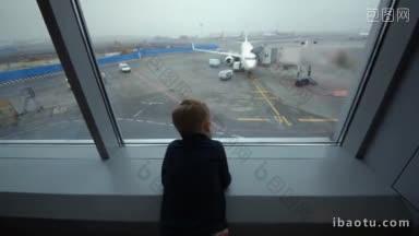 好奇的小男孩看着窗外的机场区域与飞机登机时，他用他的手显示飞机