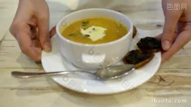 在咖啡馆或餐厅里用勺子搅拌汤的妇女用奶油和意式烤面包的热汤特写镜头