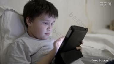 十几岁的男孩用触控板躺在床上靠在枕头上用平板电脑娱乐