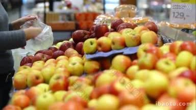 超市里的女人走到<strong>水果</strong>柜台，挑选苹果，把它们放进塑料袋里