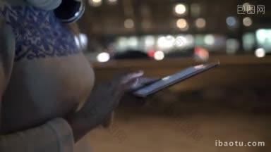 斯坦尼康拍摄的一个女人在平板电脑上输入信息，她独自走在户外的晚上