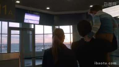 母亲、父亲和儿子在机场候机楼欣赏日落时窗外的景色