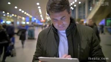 慢镜头中，一名身穿夹克的商人在车站使用<strong>电子平板电脑</strong>，行人正从旁边经过