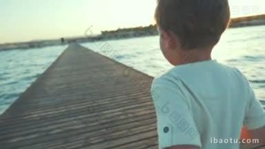 慢动作<strong>斯</strong>坦尼康回拍一个小男孩在日落时沿着海上的木码头奔跑