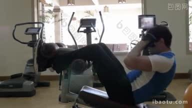 慢动作的一个人在现代化的健身中心锻炼，他做仰卧起坐在腹部长凳上，然后停止