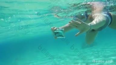 慢动作的女人在浮潜与智能手机在防水的情况下在水下自拍或拍照