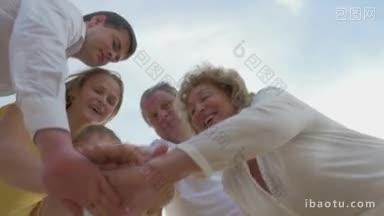 低角度拍摄的一个大家庭把手放在一起，把他们举起来