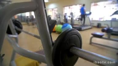 慢动作的现代健身房在健身中心胸部按压锻炼者在前景和男人在跑步机上跑步在背景